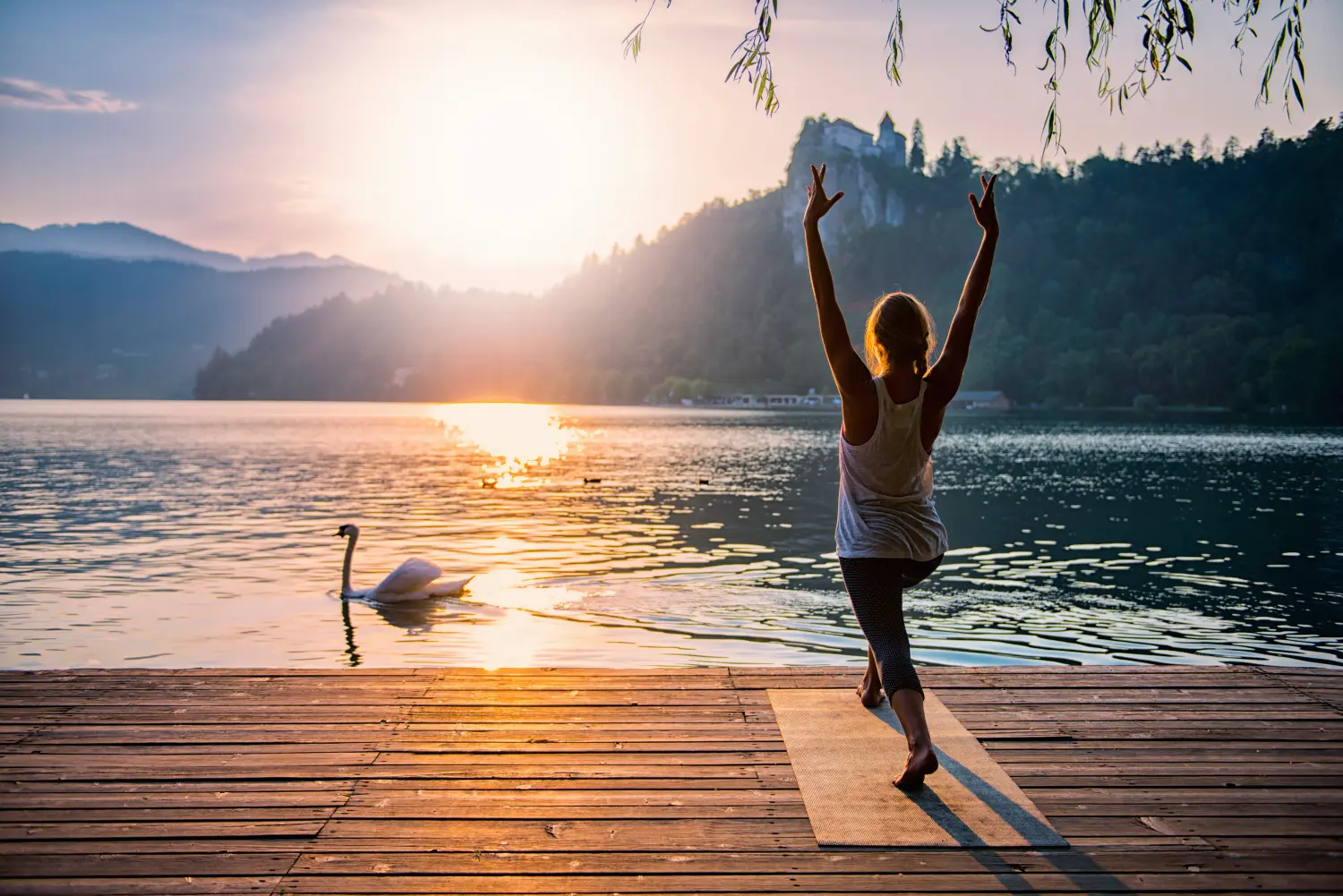 Sonnengruß-Yoga. Junge Frau macht Yoga am See bei Sonnenuntergang
